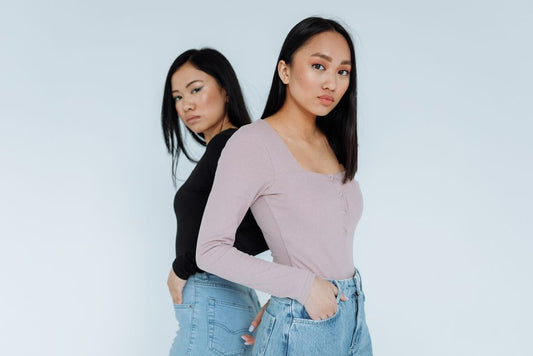 Two Asian women wearing long sleeves, posing confidently in a studio with a white background.
